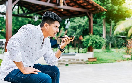 Hispanic man sitting outdoors talking on phone during telehealth appointment
