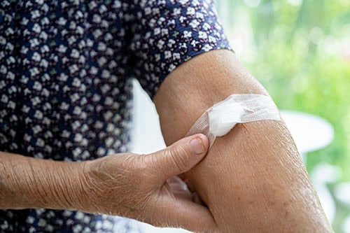 Older man holding on cotton swab and bandage after having his blood drawn