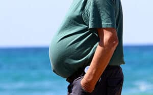 Close-up view of overweight man walking on beach