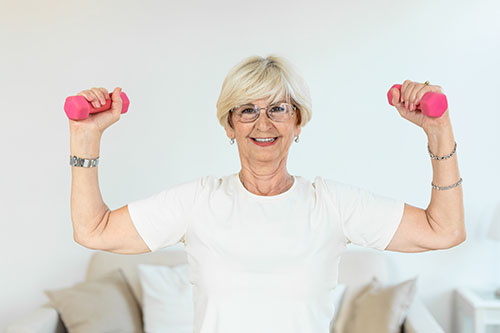 Smiling senior woman holding up pink hand weights